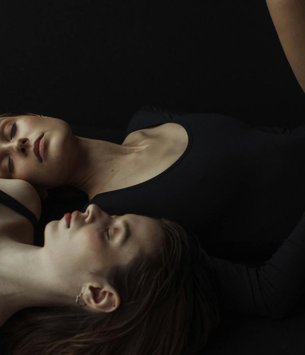 Woman in a peaceful yoga pose against a dark, calm background.